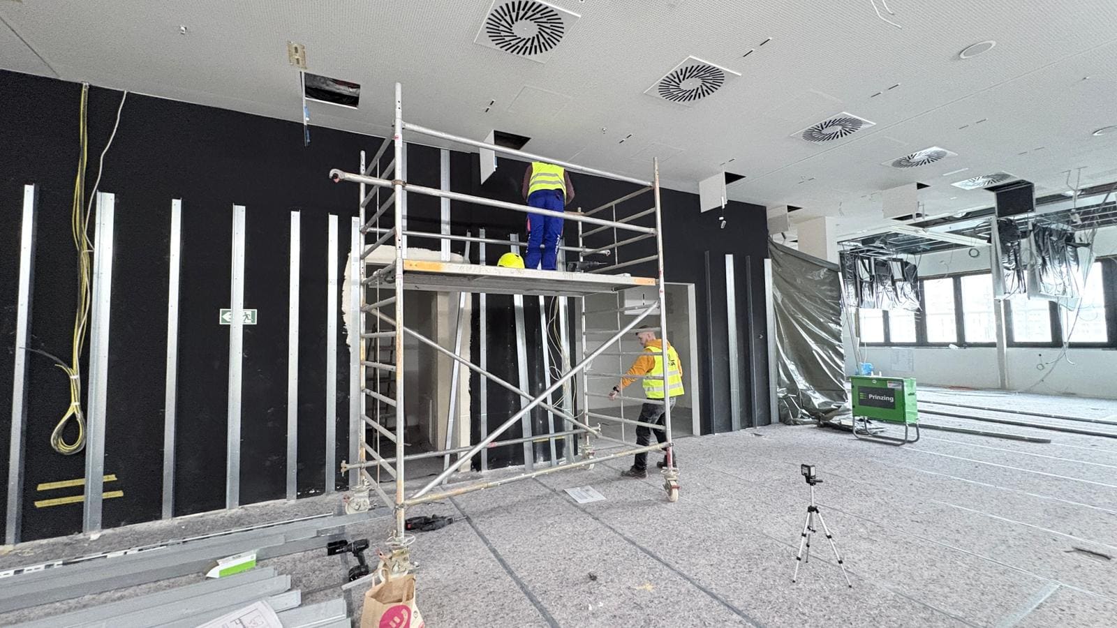 Akustikwand im Ausbau mit sichtbarer Unterkonstruktion und Montagearbeiten